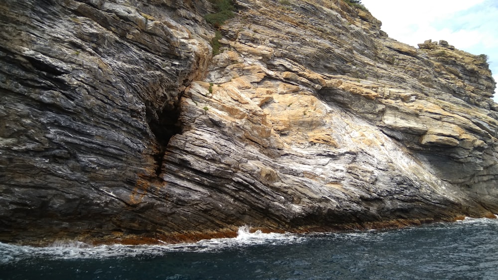 brown and green rock formation beside body of water during daytime