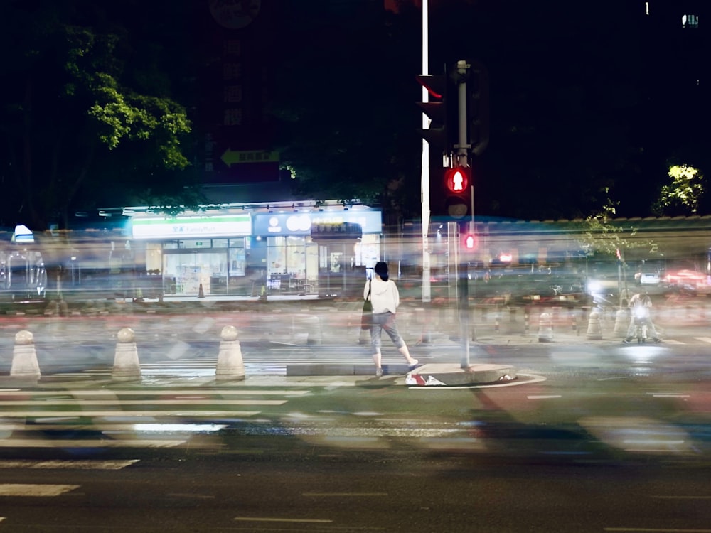 woman in white shirt and white pants standing on sidewalk during night time