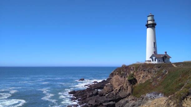 A serene lighthouse standing tall against a calm blue sky, symbolizing steady guidance.