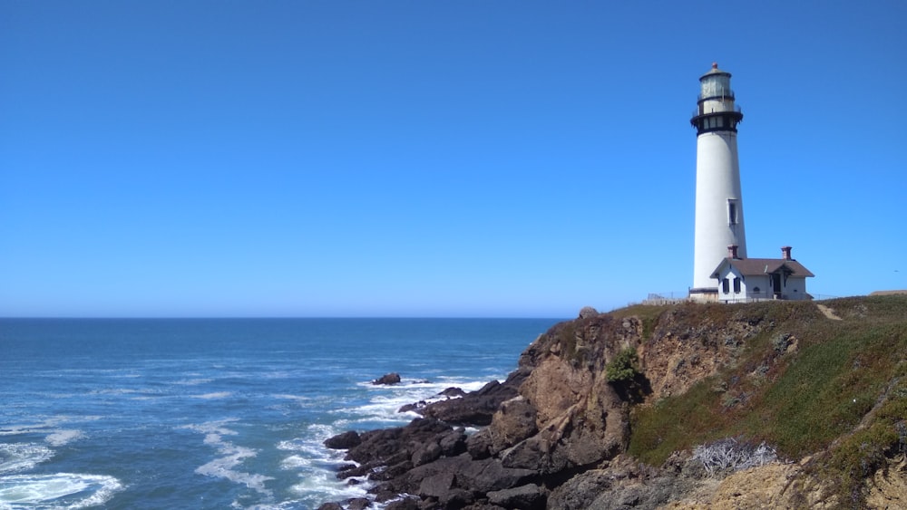 white lighthouse on brown rocky shore during daytime