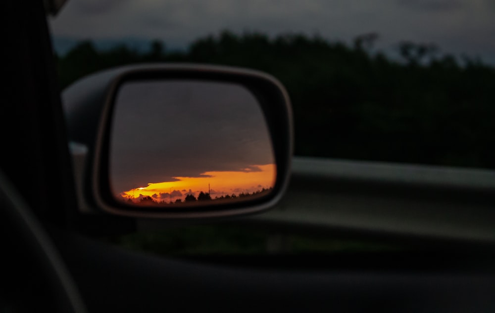 car side mirror reflecting green trees during daytime