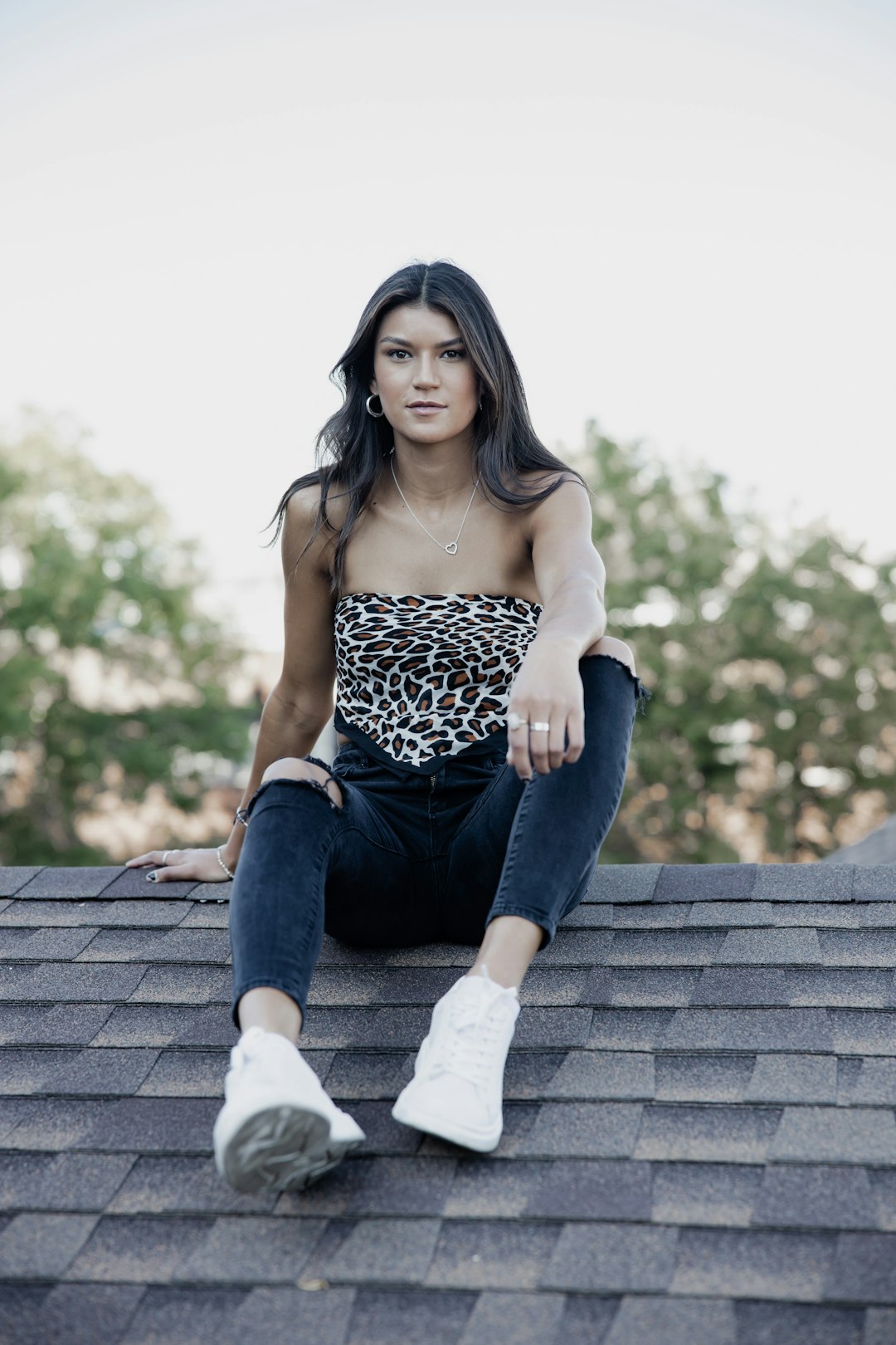 woman in black and white tank top and blue denim jeans sitting on brown brick wall