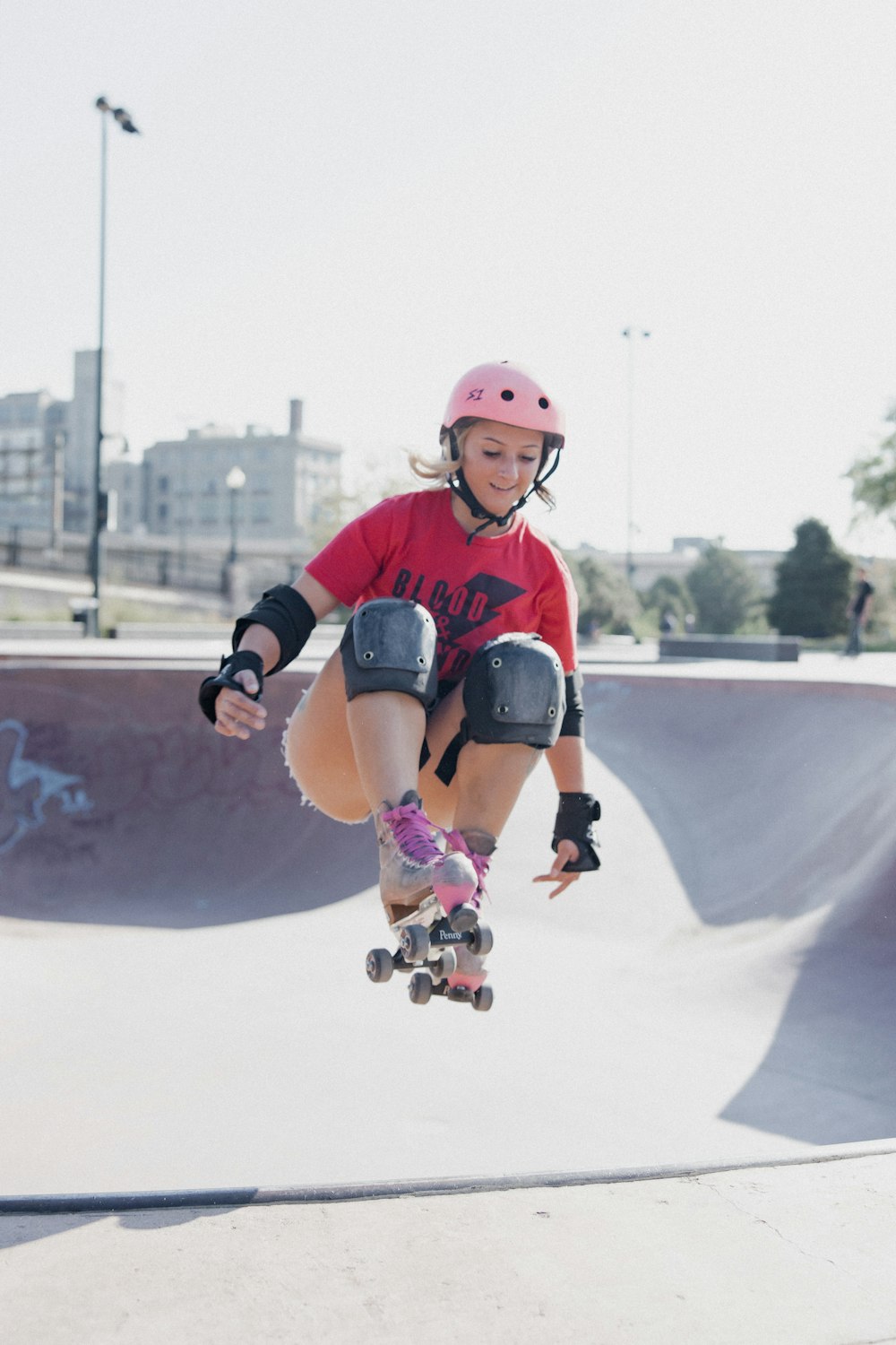 girl in red and black jersey shirt and helmet riding on white and black skateboard during