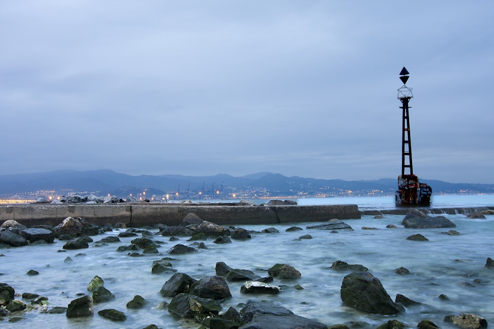 black and white lighthouse near body of water under white sky during daytime