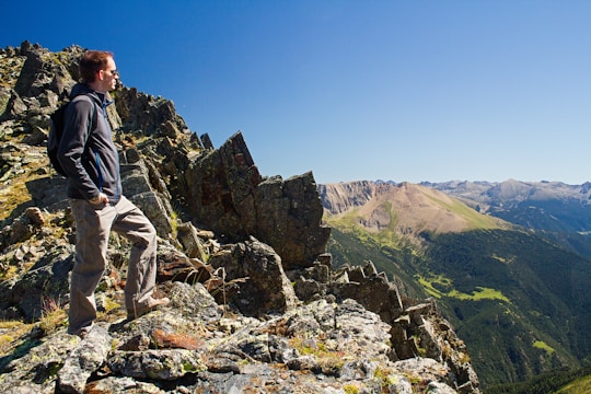 A person standing on a mountain peak, looking at a vast landscape.