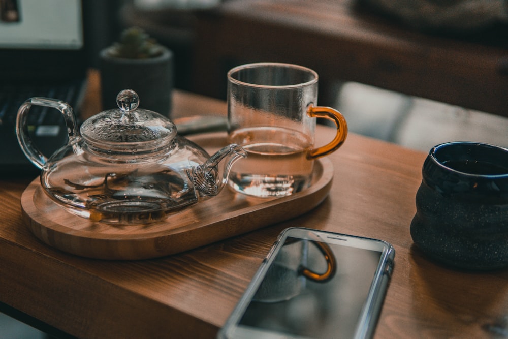 théière en verre transparent et tasse à thé en verre transparent sur table en bois brun