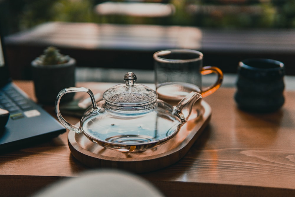 clear glass teapot on brown wooden tray