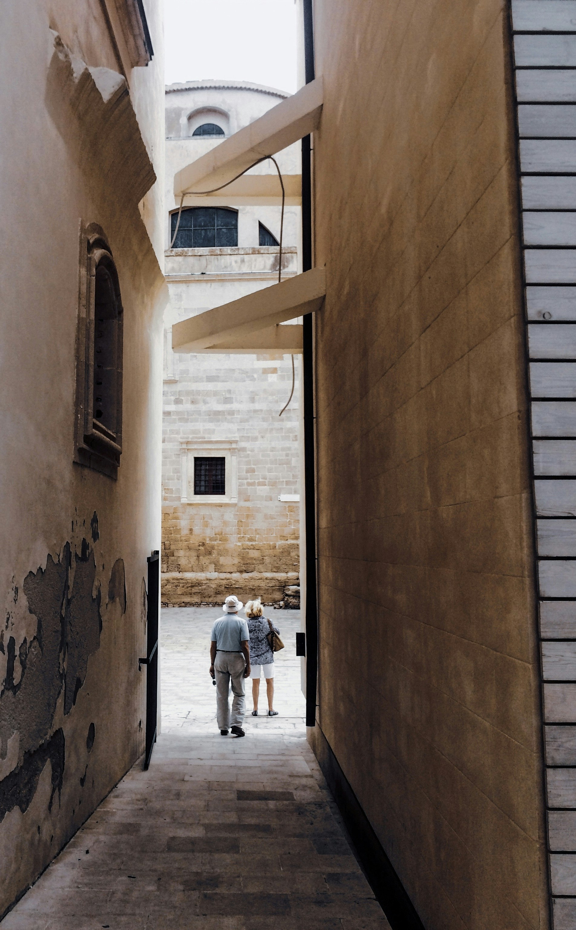 man in white t-shirt and blue denim jeans walking on hallway