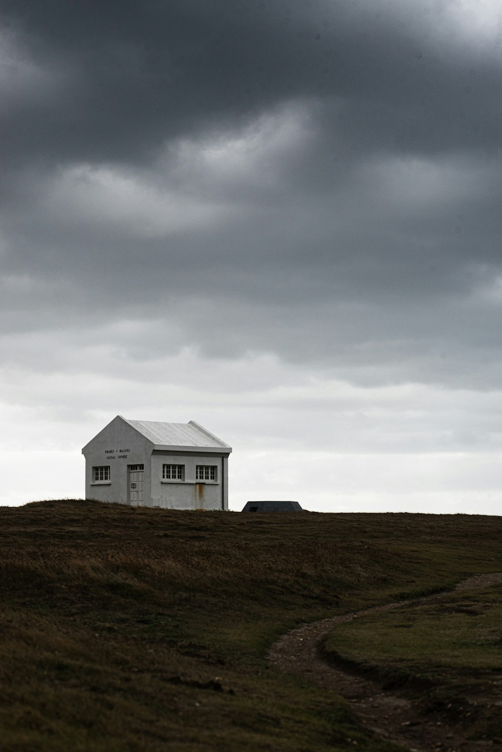 casa di legno bianca sul campo di erba verde sotto nuvole bianche