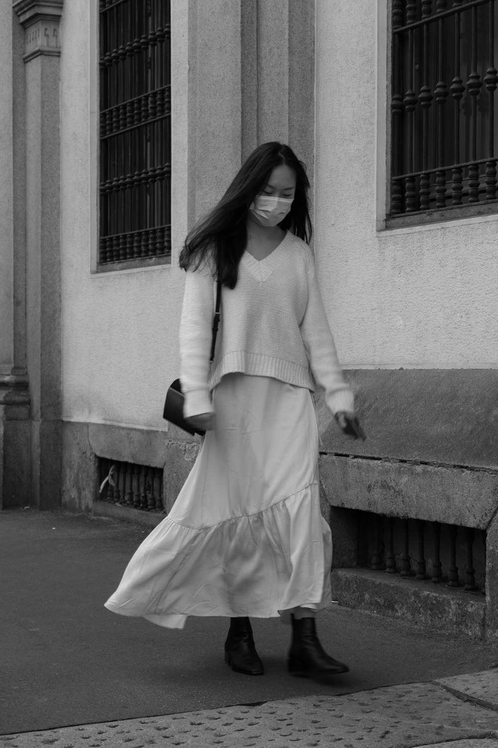 woman in white long sleeve dress standing on sidewalk during daytime