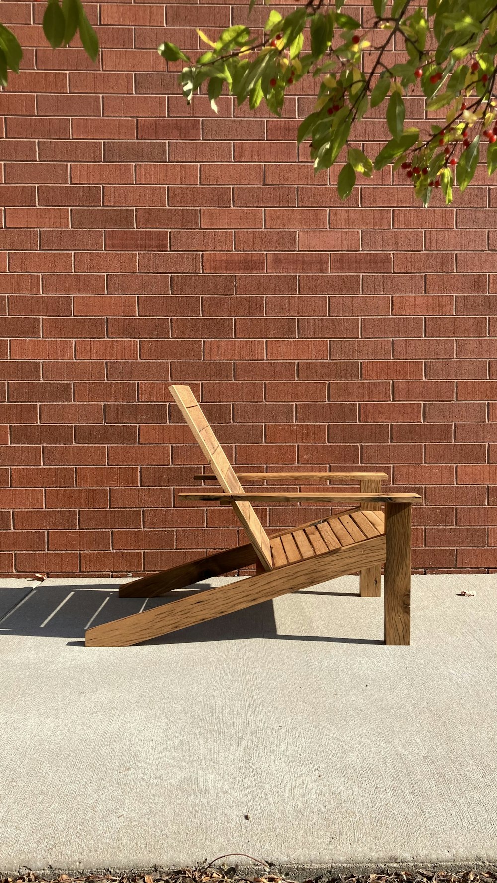 chaise pliante en bois marron à côté d’un mur de briques brunes