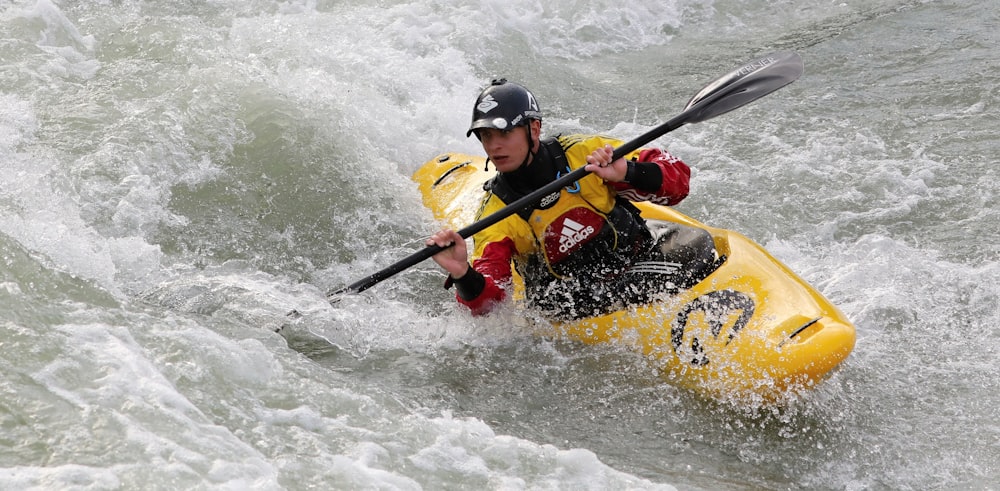 man in red jacket riding yellow kayak on water during daytime