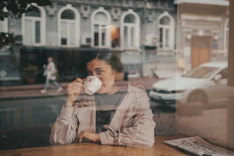 woman in white long sleeve shirt drinking from white ceramic mug