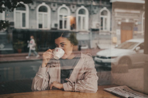 woman in white long sleeve shirt drinking from white ceramic mug