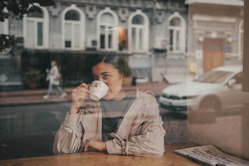 woman in white long sleeve shirt drinking from white ceramic mug