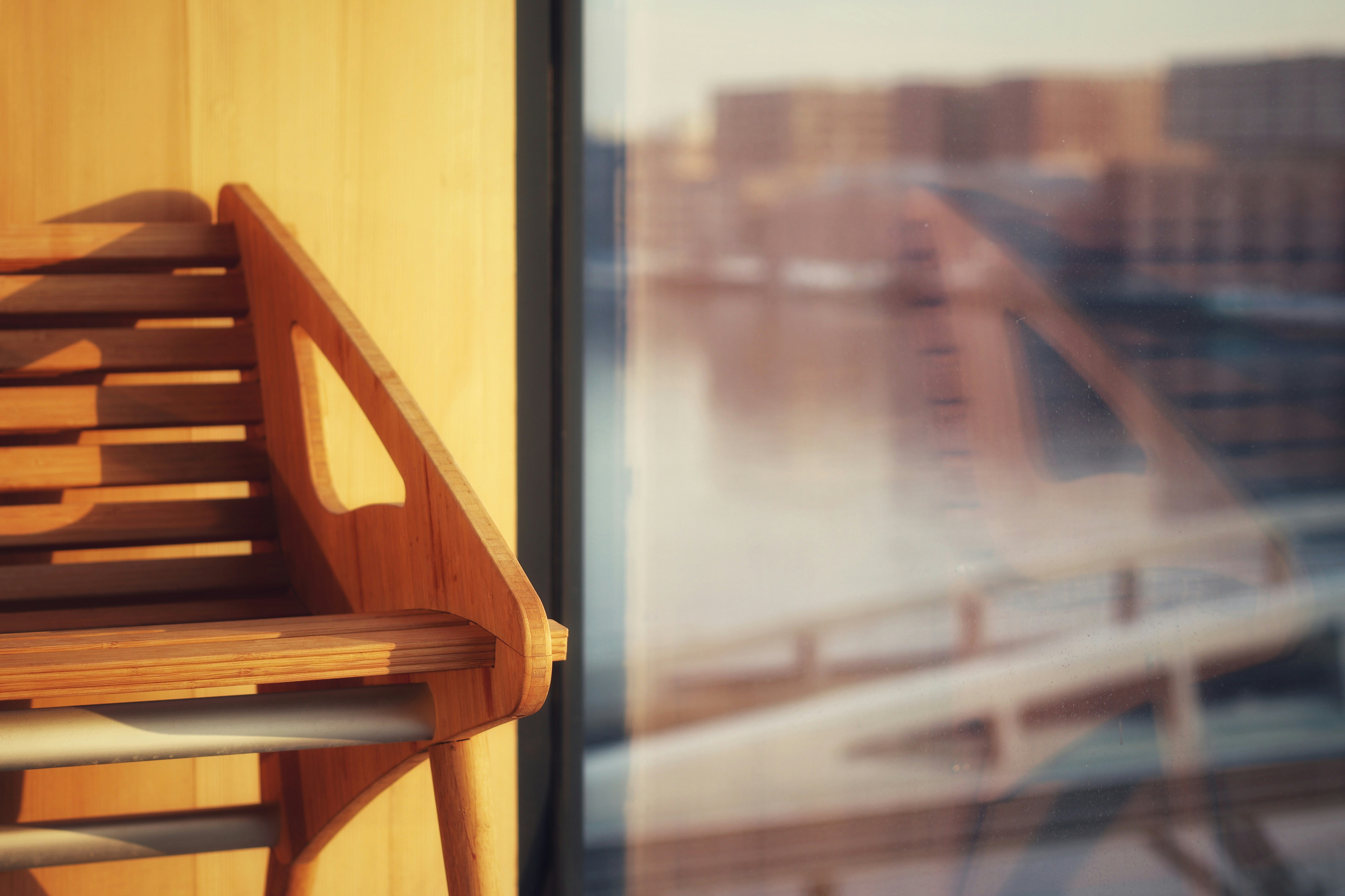 Empty bench beside a rain-wet window, overcast light, blurred street beyond glass, quiet isolation