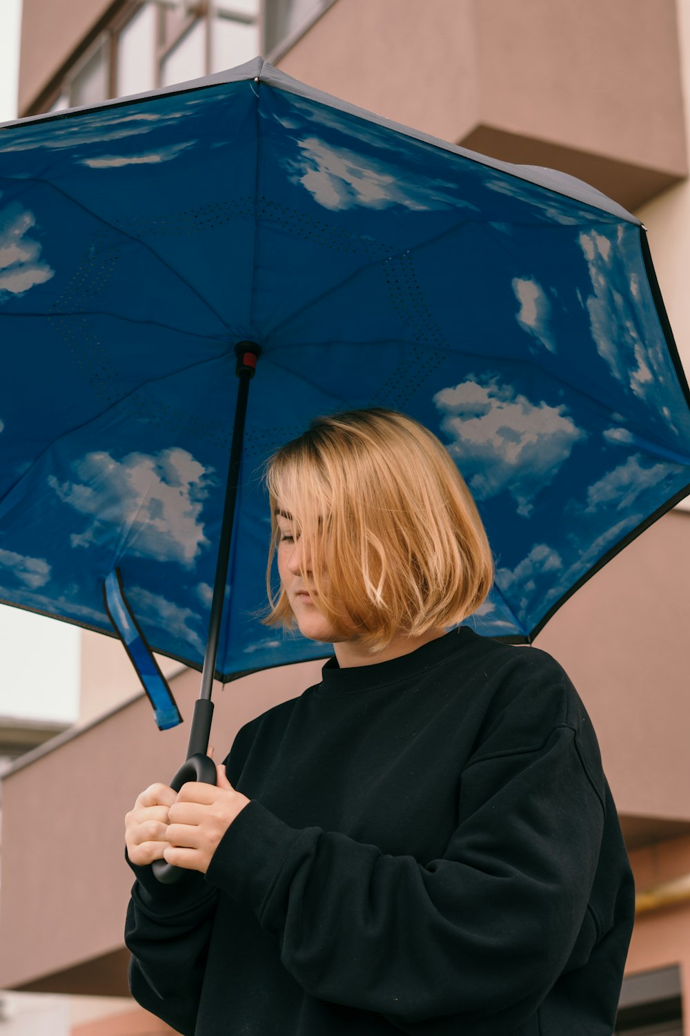 woman in black long sleeve shirt holding blue umbrella