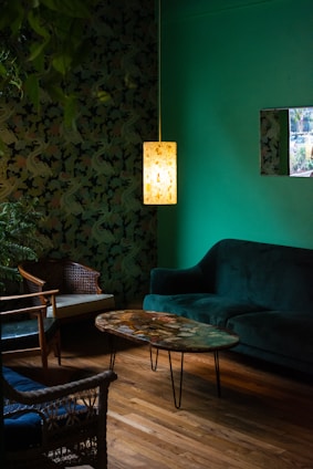 Un salon d'appartement, avec un canapé, des fauteuils, une table basse et un luminaire