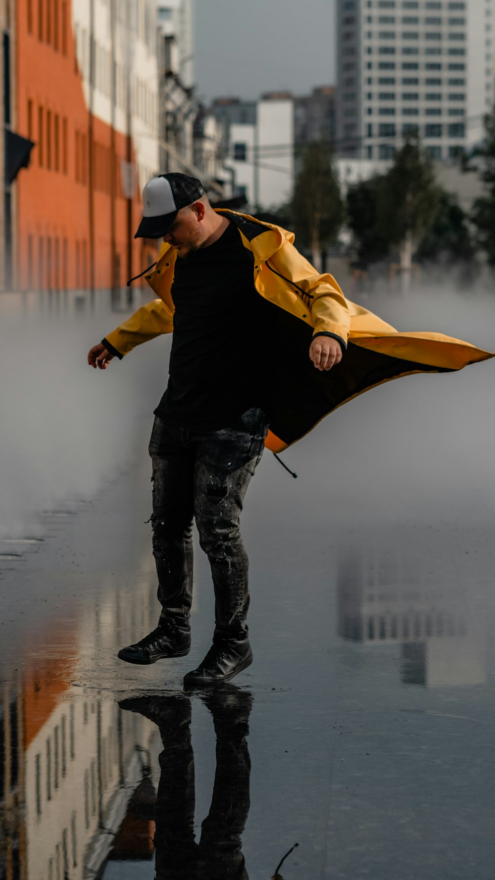 man in black jacket and black pants holding yellow umbrella