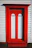Front view of a colorful modern wooden door installed on a sunny suburban home.