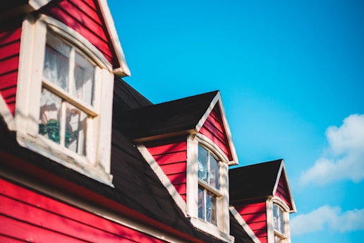 A freshly painted house exterior with bold red and white accents under a clear sky.