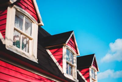 A house with a freshly painted red roof under a clear blue sky, highlighting the paint’s durability and shine.