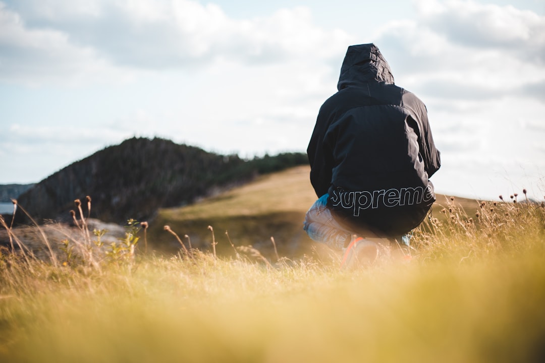 person in black hoodie standing on brown grass field during daytime