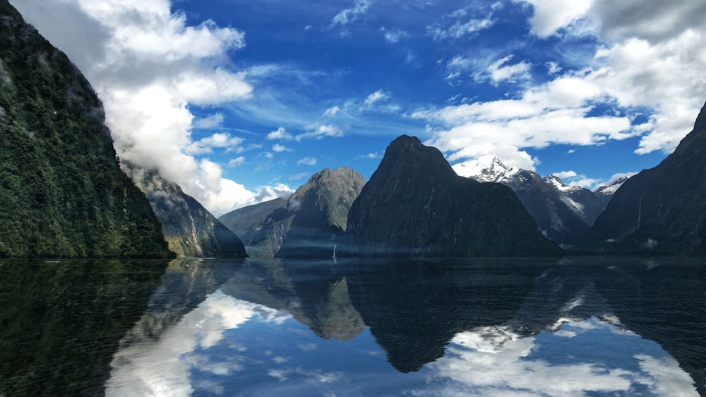 lago perto da montanha sob céu azul e nuvens brancas durante o dia