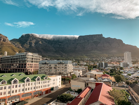 White and brown concrete buildings near gray mountain under blue sky during daytime — Cape Town, South Africa