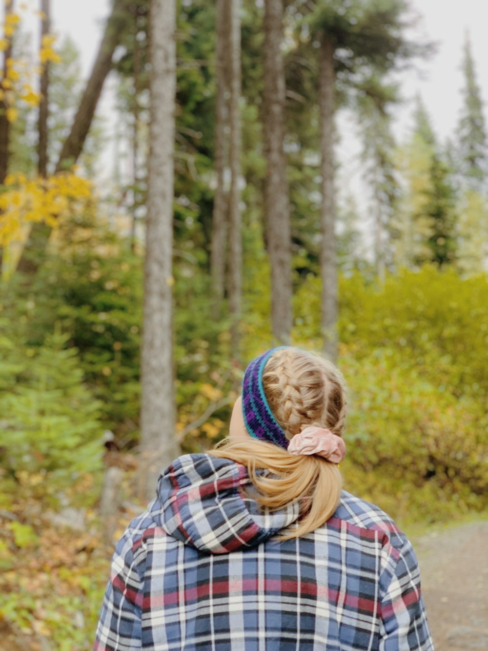 woman in white red and blue plaid scarf standing in forest during daytime