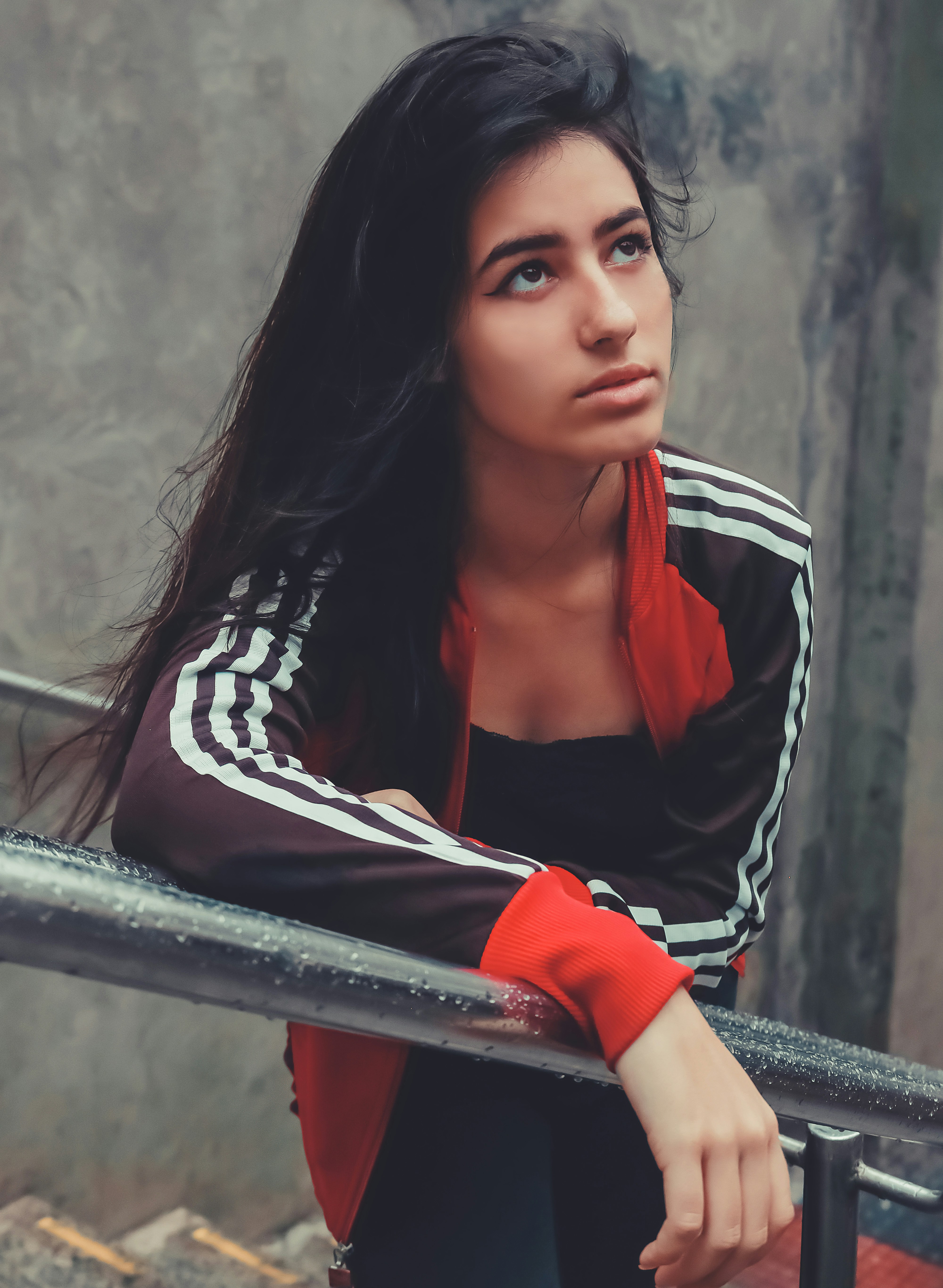 woman in black and white jacket leaning on gray metal railings