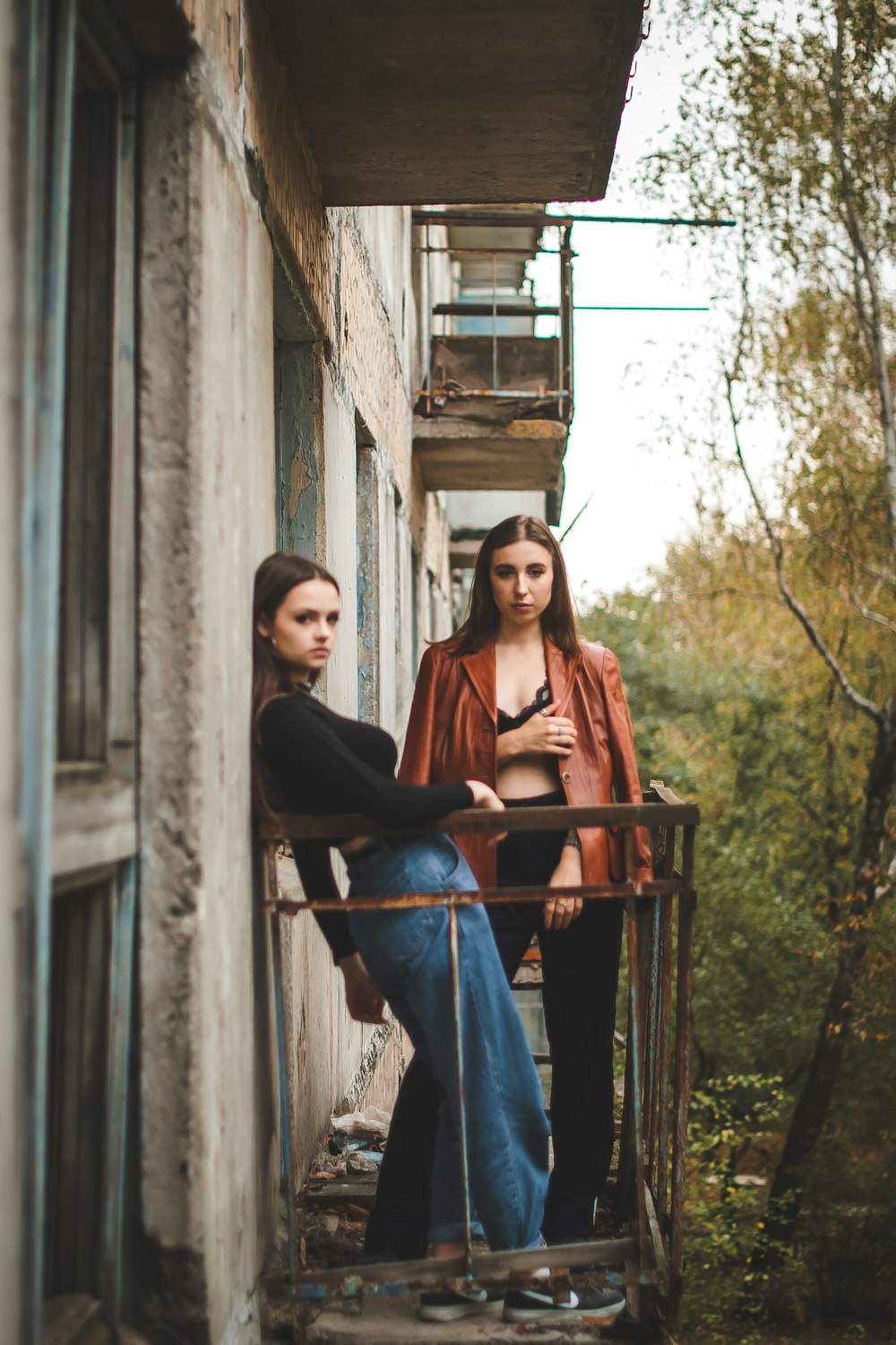 woman in black long sleeve shirt and blue denim jeans sitting on blue metal railings during