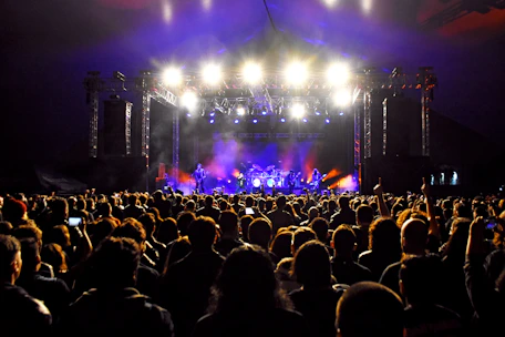 A lively stage setup with colorful lights and a band performing, captured from the audience perspective.