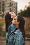 woman in blue denim jacket kissing womans cheek