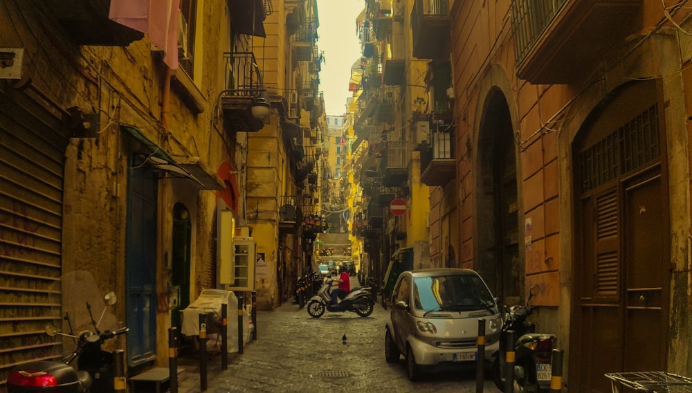 cars parked on side of the road in between buildings during daytime