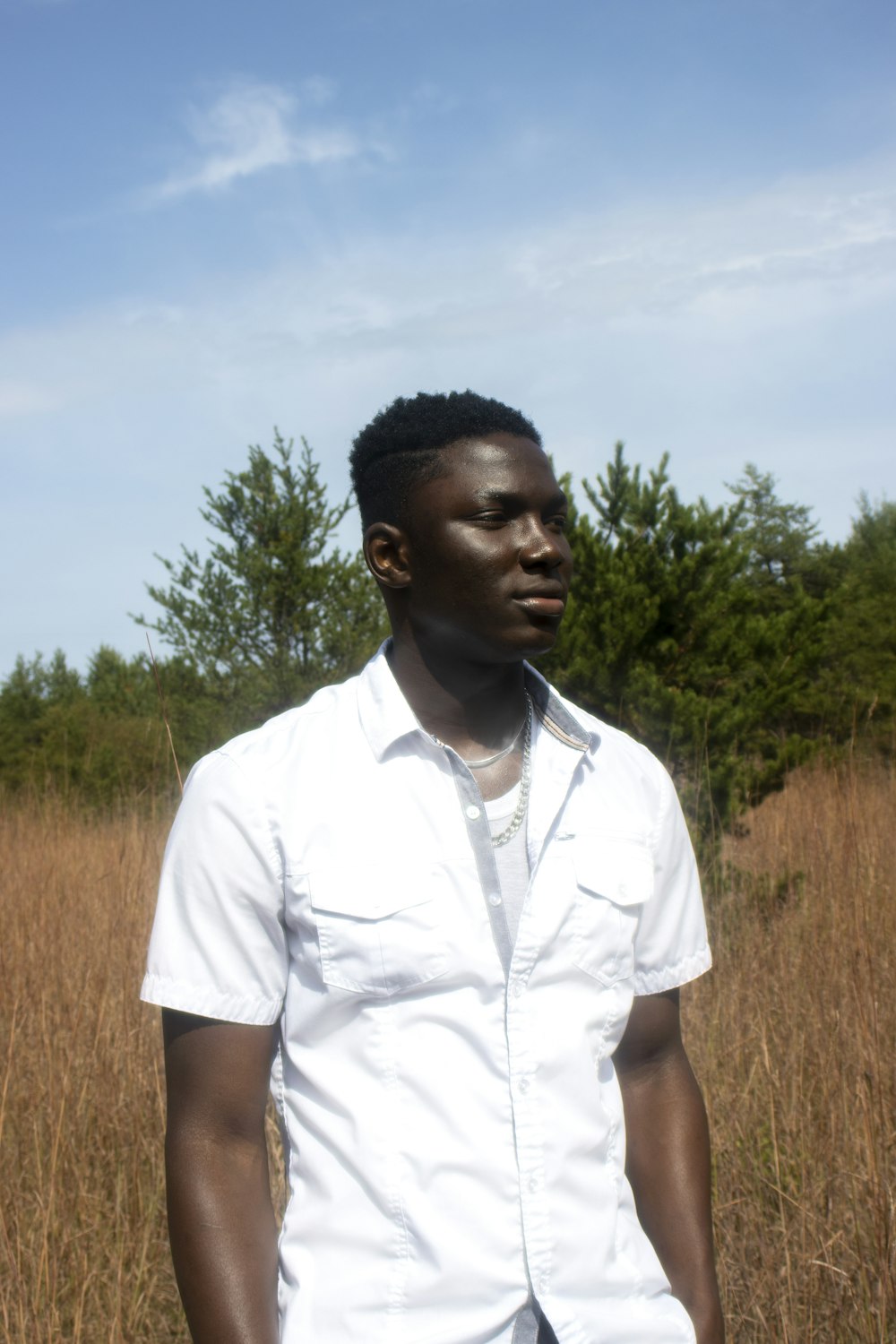 man in white button up shirt standing on brown grass field during daytime