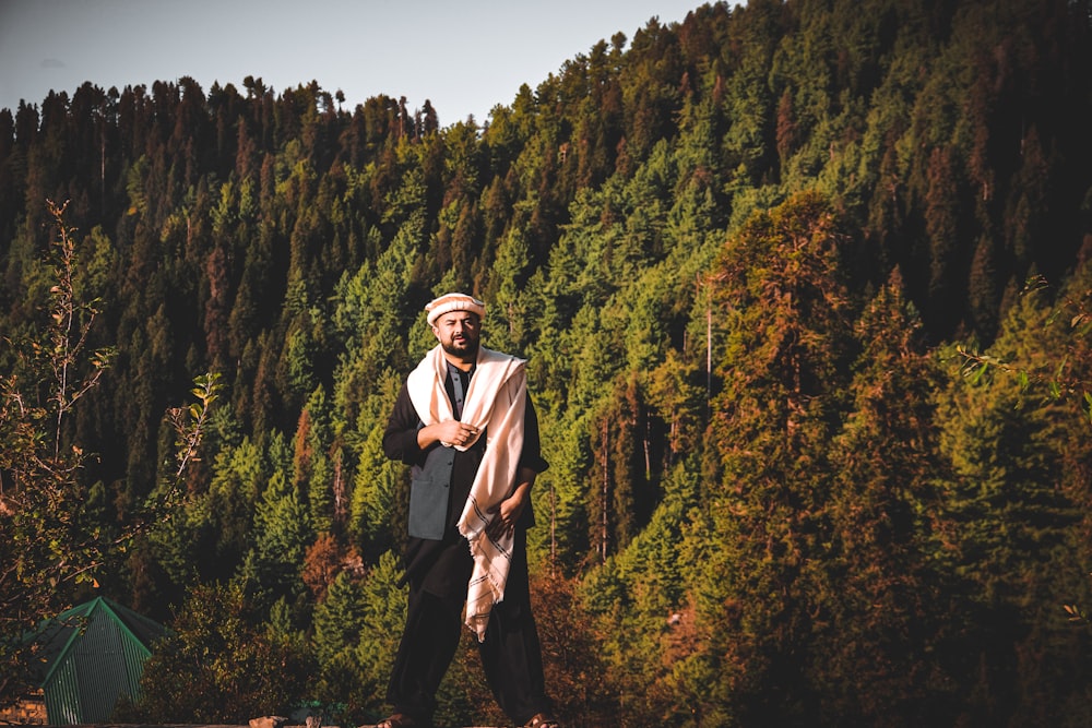 man in black suit standing near green trees during daytime