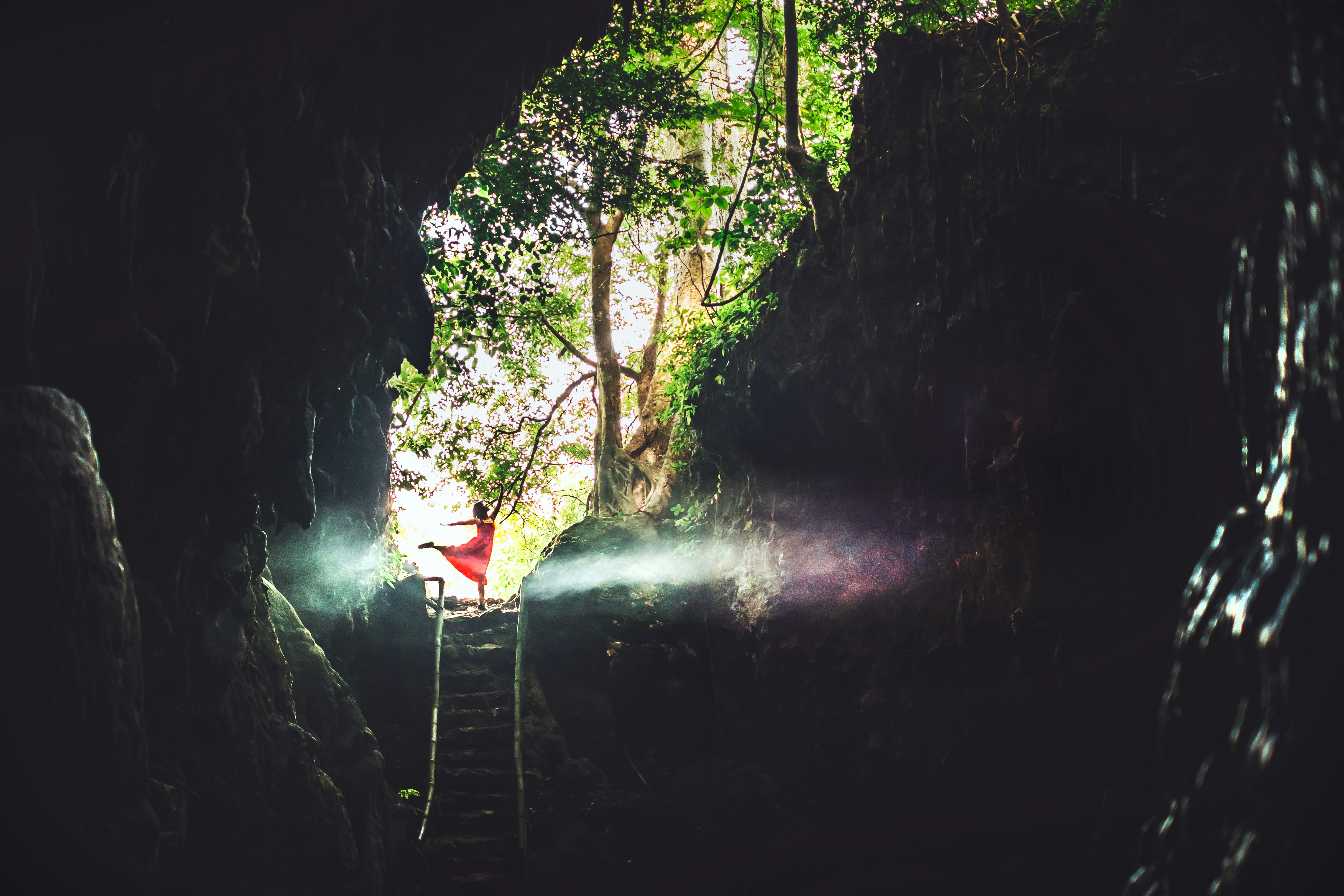 person in red jacket standing on bridge over river, 