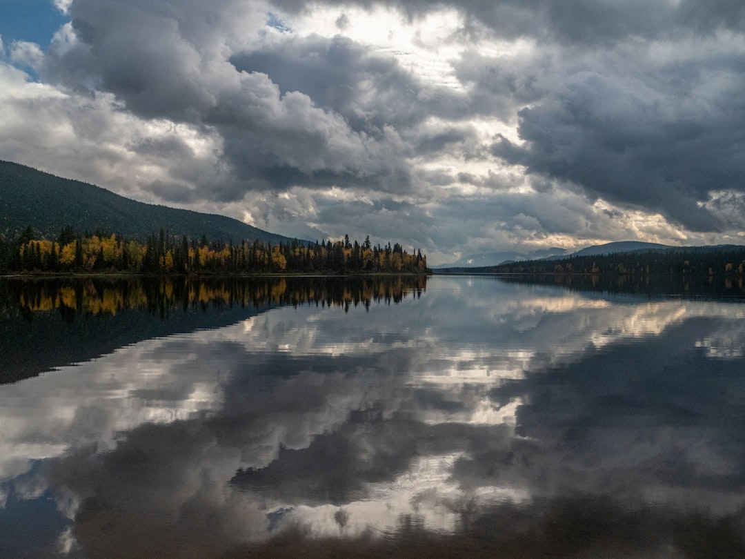 body of water near mountain under cloudy sky during daytime