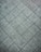 A textured, grey tiled surface with a repeated diamond pattern. The tiles appear to be made of stone or concrete and have a rough, weathered look.