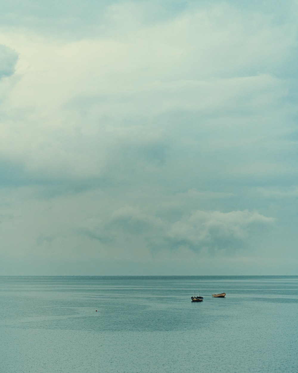 2 people riding on boat on sea under white clouds and blue sky during daytime