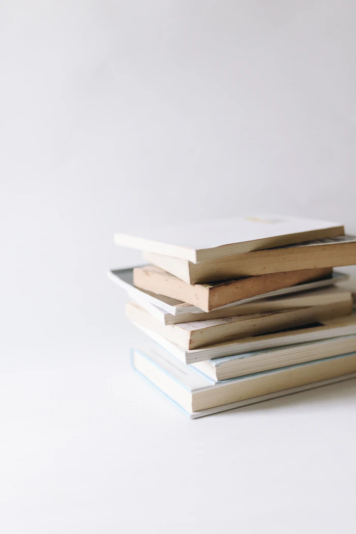 Stack of pale paperback books on a white surface