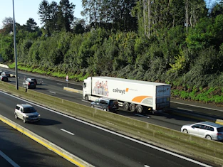 A large truck driving on a highway surrounded by green fields.