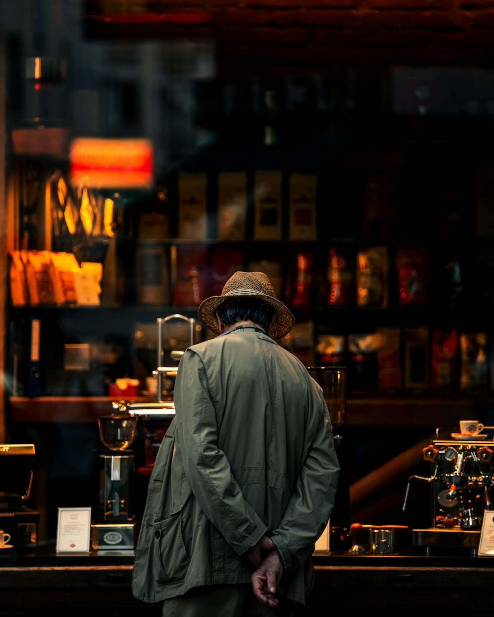 man in gray jacket standing in front of brown wooden shelf