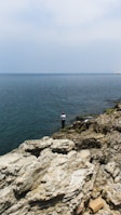 An instructor demonstrating bottom fishing techniques by a rocky shoreline.