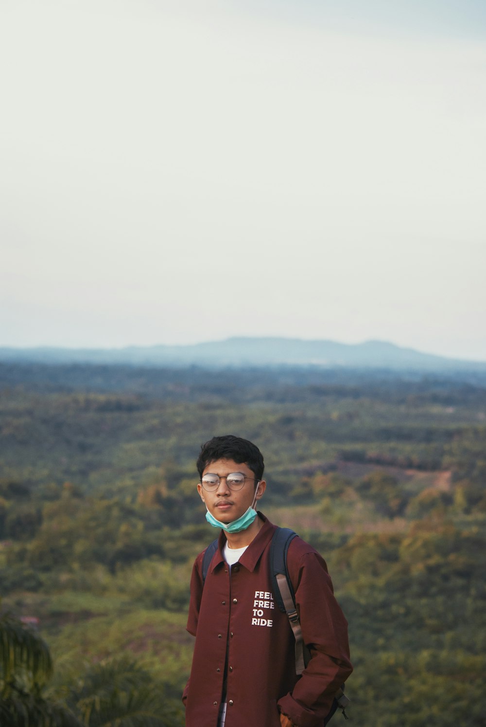 man in red jacket standing on hill during daytime