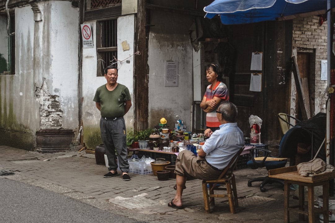 man in green crew neck t-shirt and black pants sitting on brown wooden chair during