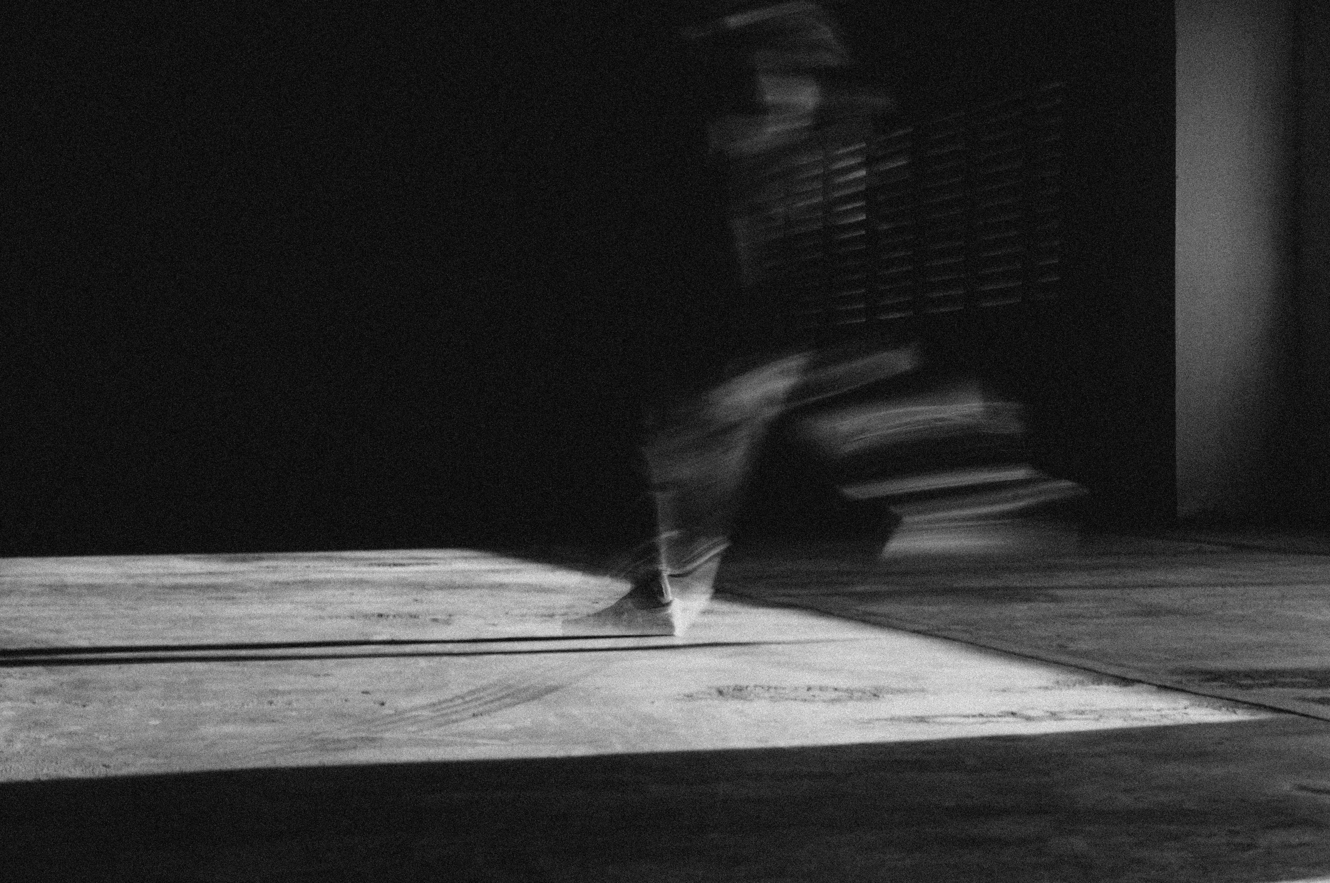 grayscale photo of person standing on wooden floor