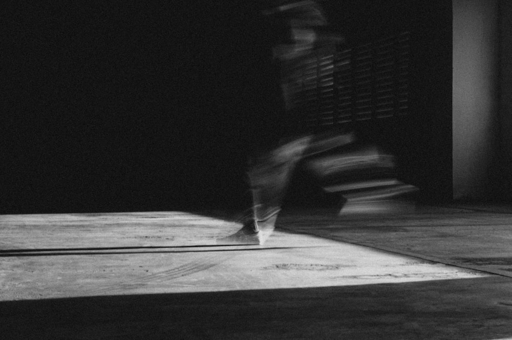 grayscale photo of person standing on wooden floor