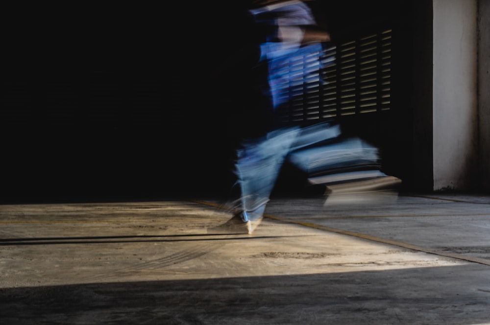 person in black shirt and blue denim jeans walking on brown wooden floor